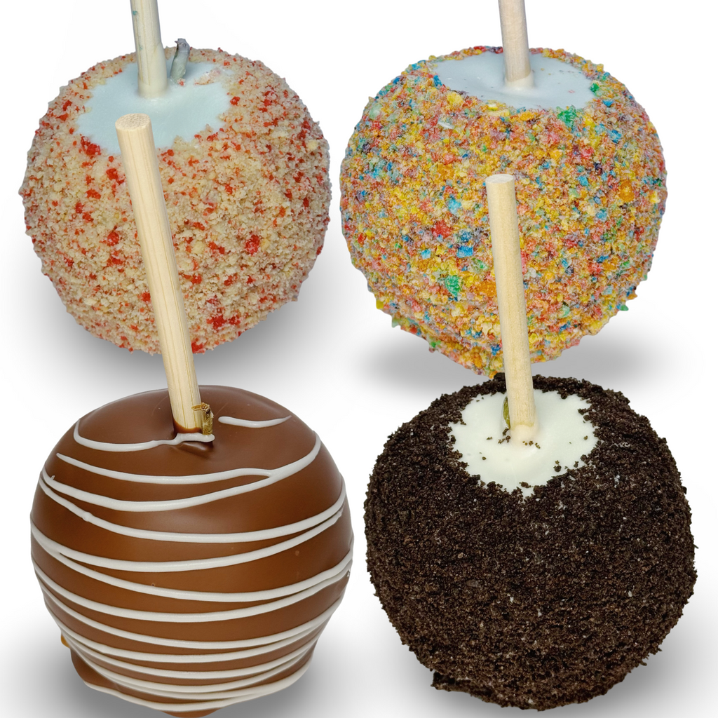 Four assorted caramel apples with different coatings on a white background. A white chocolate caramel apple topped with strawberry shortcake. A white chocolate caramel apple with fruity cereal topping A milk chocolate caramel apple with a white chocolate drizzle. A white chocolate caramel apple with Oreo topping.
