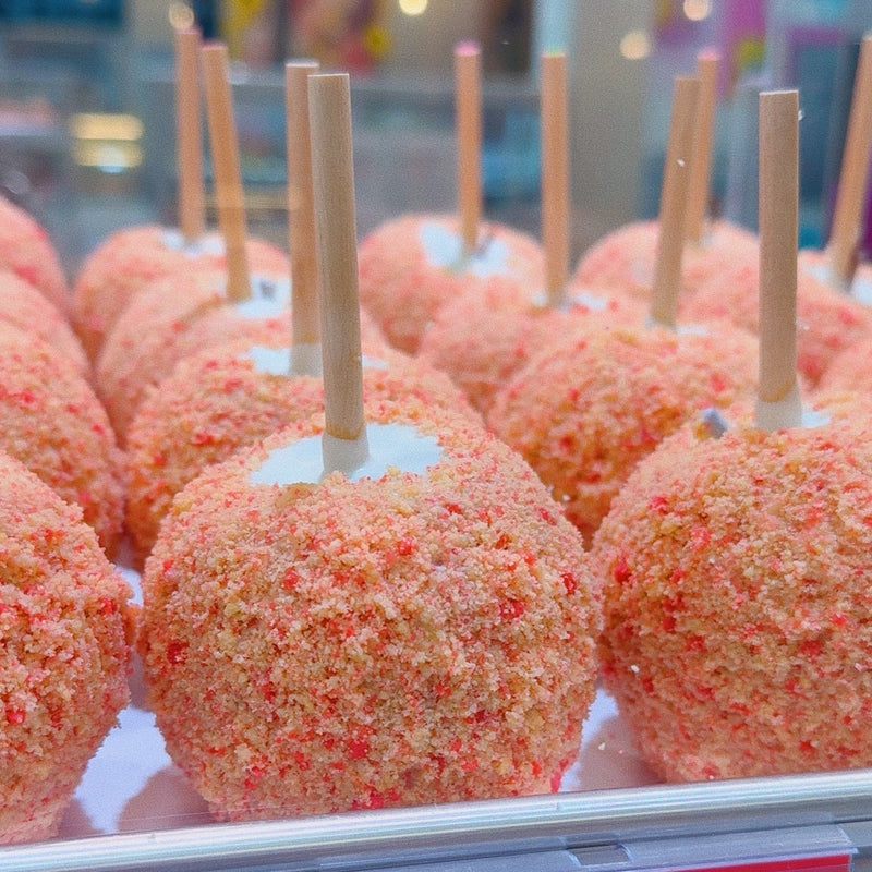 Tray of strawberry shortcake caramel apples coated in white chocolate and strawberry shortcake crumble.